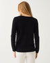 blonde female wearing black sweater standing backwards on a white background 