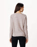brunette female wearing light brown sweater standing backwards on a white background 