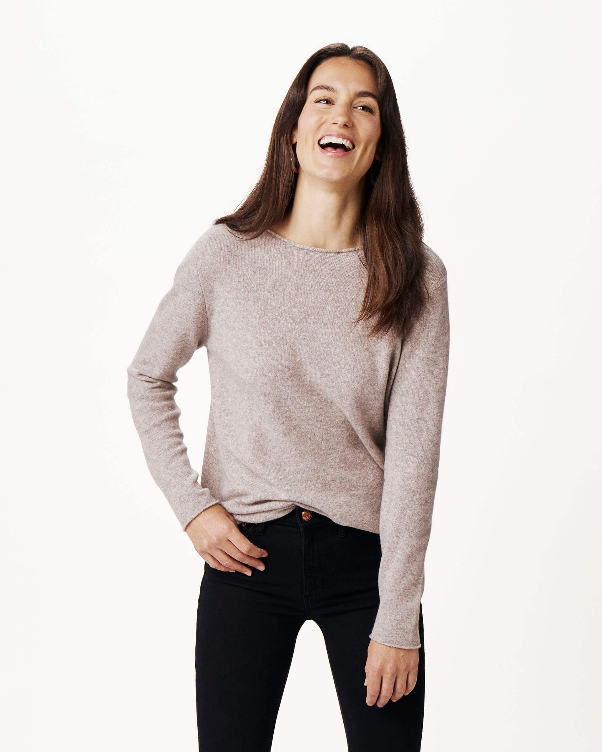 brunette female wearing light brown sweater and laughing on a white background 