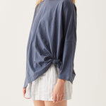 close up of female wearing dark blue tee-shirt with side slits tied in a knot on a white background