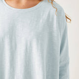 close up of female wearing light blue cotton tee shirt with crew neck on white background