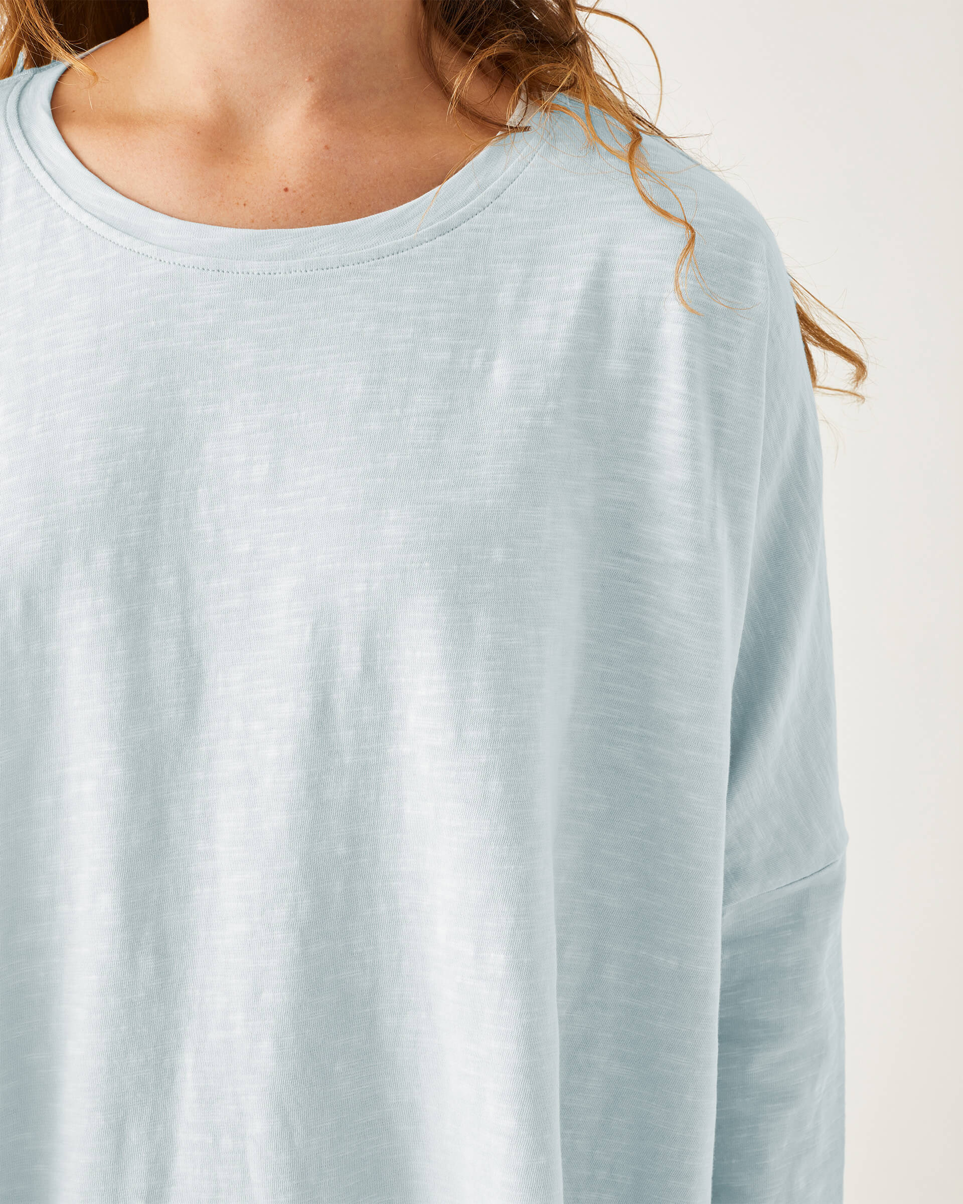 close up of female wearing light blue cotton tee shirt with crew neck on white background
