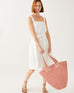 female holding red and white striped hand-braided tote bag swaying on a white background