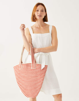 female holding red and white striped hand-braided tote bag on a white background