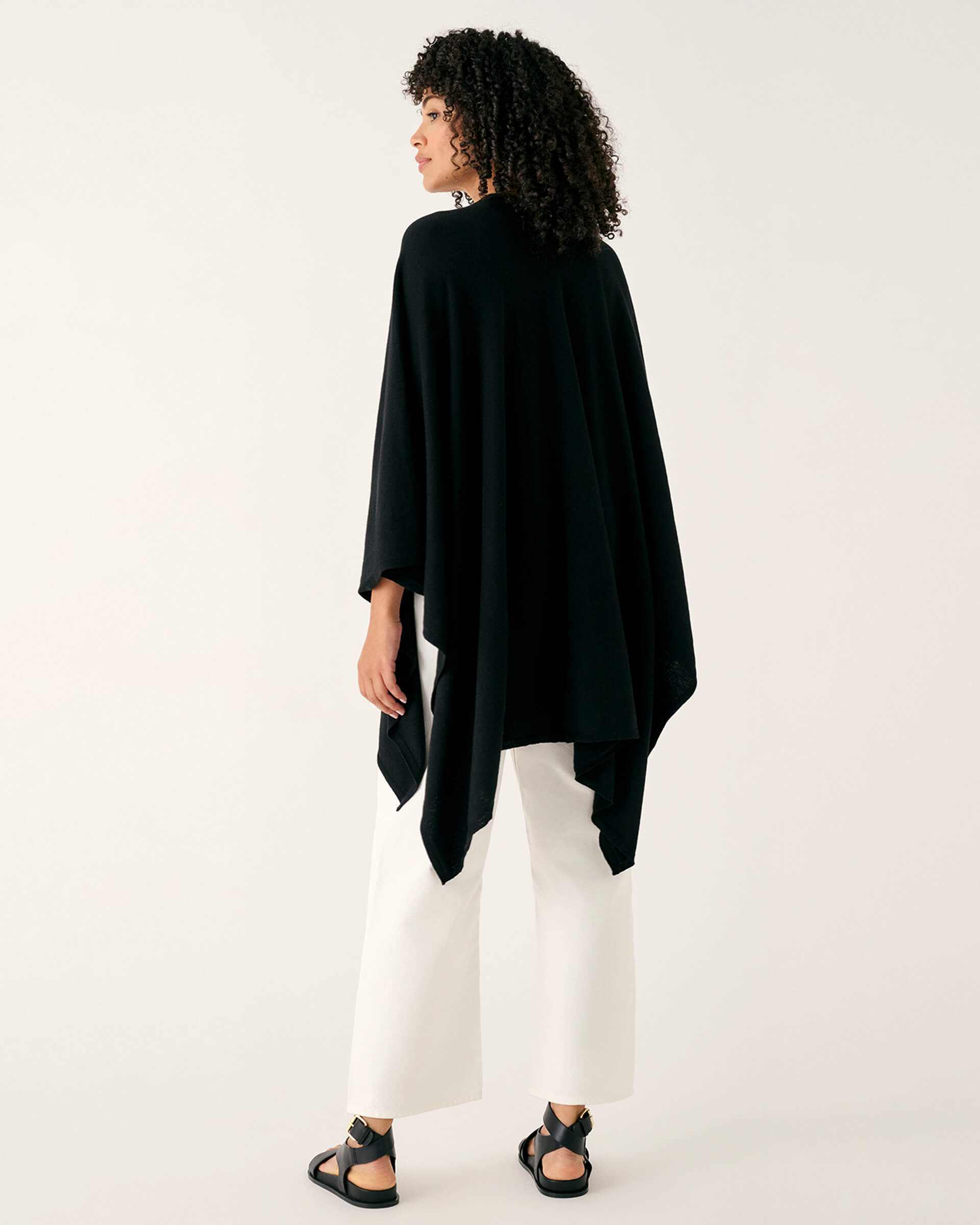 rearview of woman wearing mersea black charleston cotton cashmere wrap standing on a white background