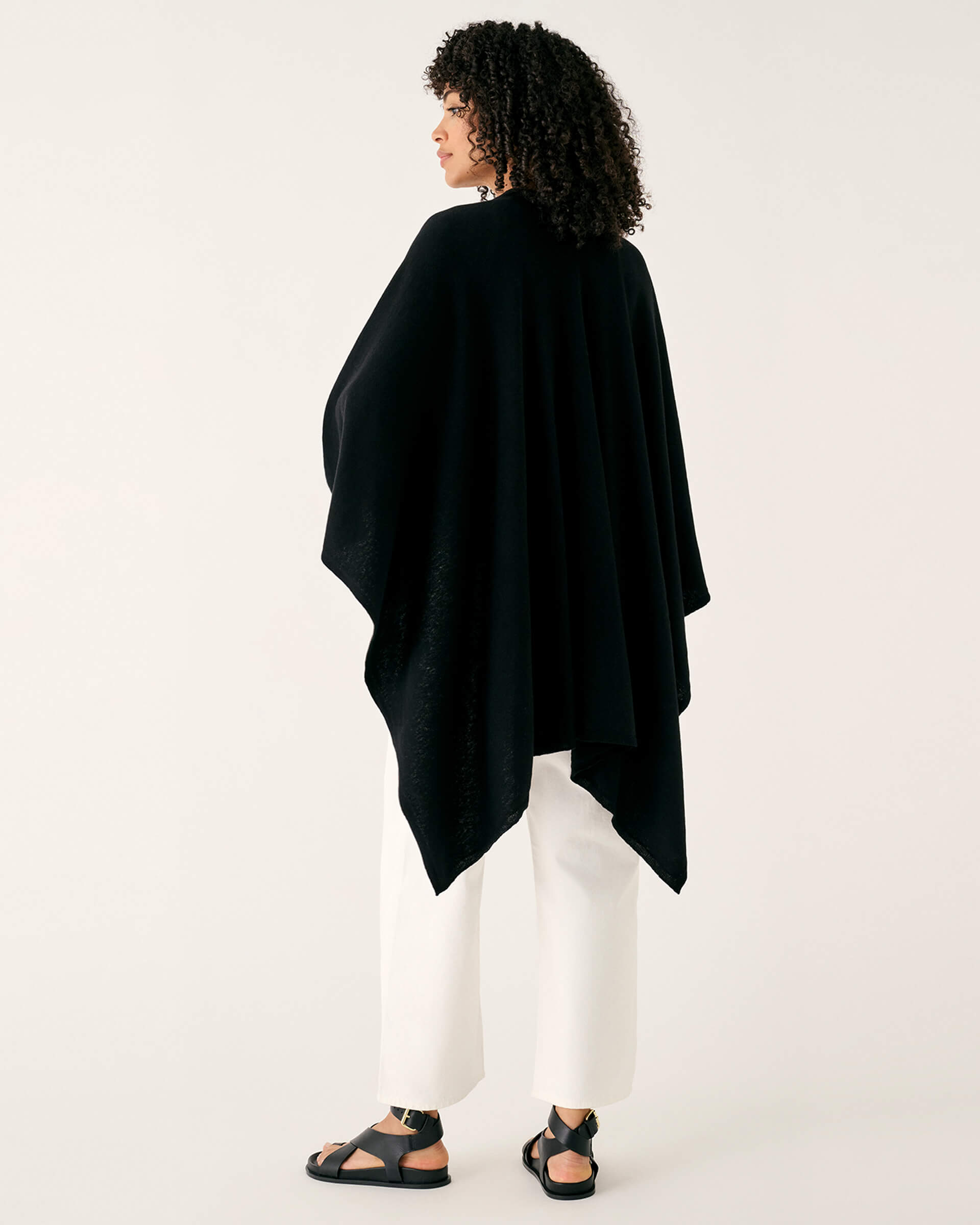 rearview of woman wearing mersea black charleston cotton cashmere wrap standing on a white background