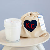 mersea colab saltaire candle sitting next to KC inside heart on candle bag on stool