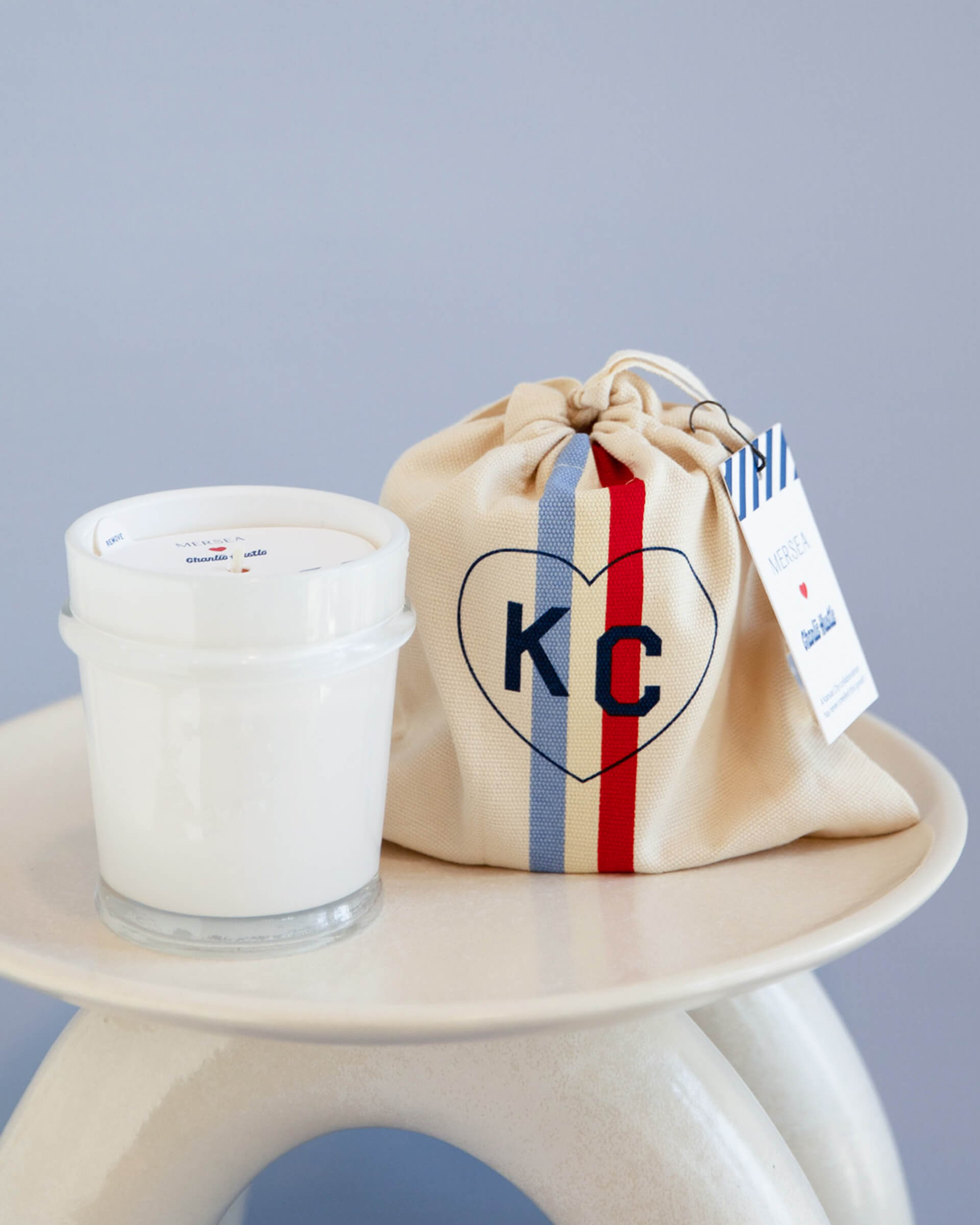 mersea colab voyager candle next to KC inside heart on candle bag on stool