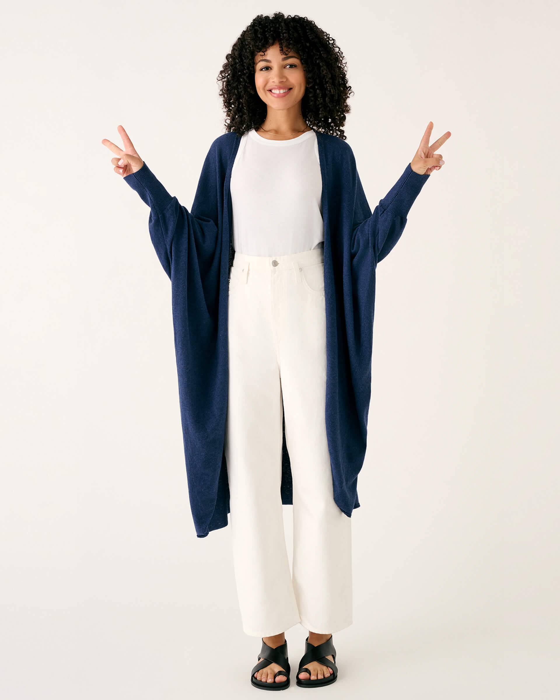 female wearing dark blue kimono sweater holding up peace signs on a white background