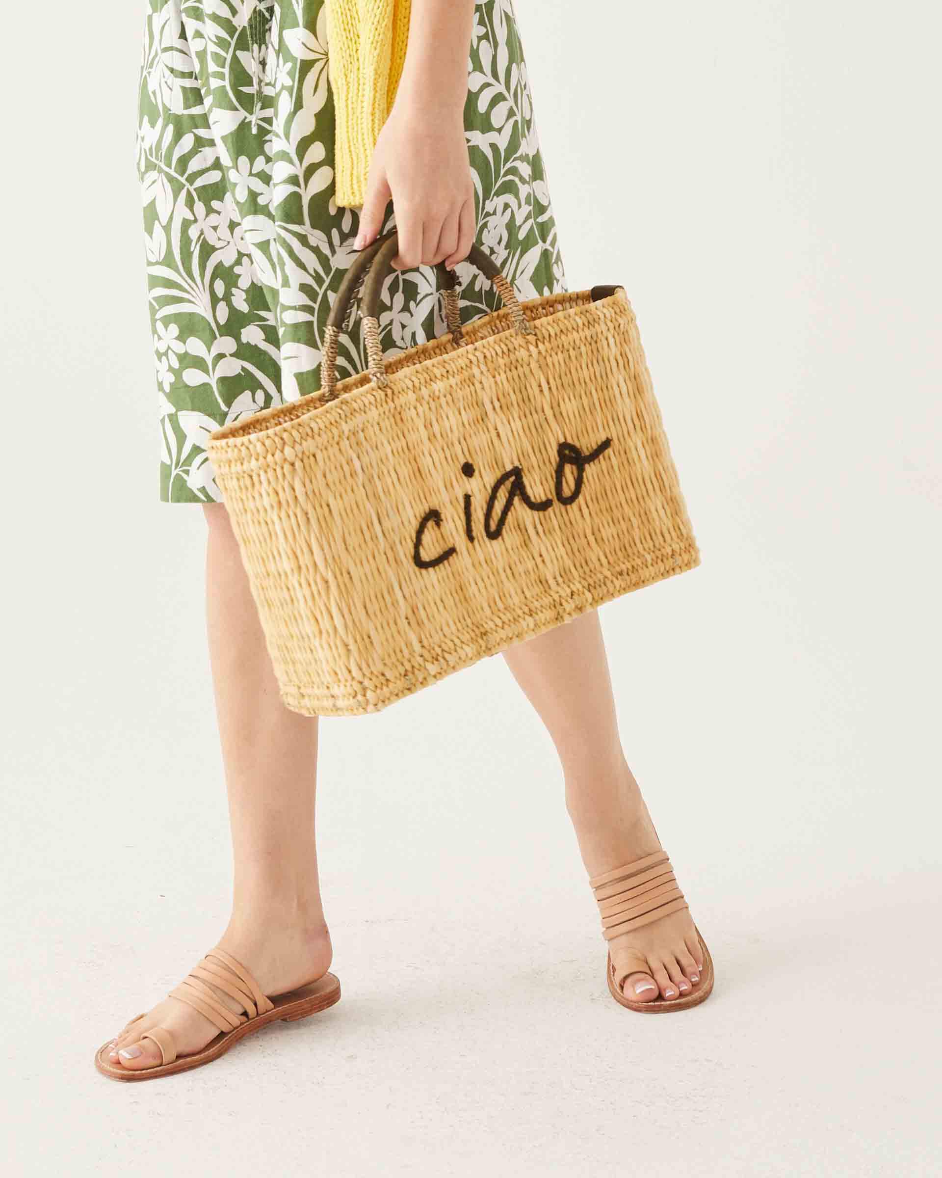 Female holdingg a straw basket with the word Ciao embroidered in black