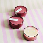 three 7 oz dark pink coconut sugar canister candles on a pink and green striped background