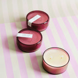 three 7 oz dark pink coconut sugar canister candles on a pink and green striped background