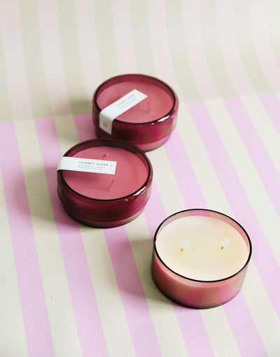 three 7 oz dark pink coconut sugar canister candles on a pink and green striped background