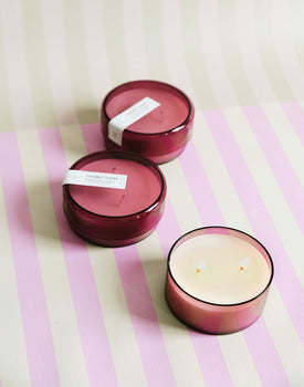 three 7 oz dark pink coconut sugar canister candles on a pink and green striped background