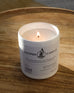 white ceramic cooper candle lit and sitting on brown wooden side table 