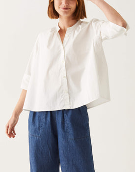 woman showcasing mersea white button down swing shirt with editor cuff