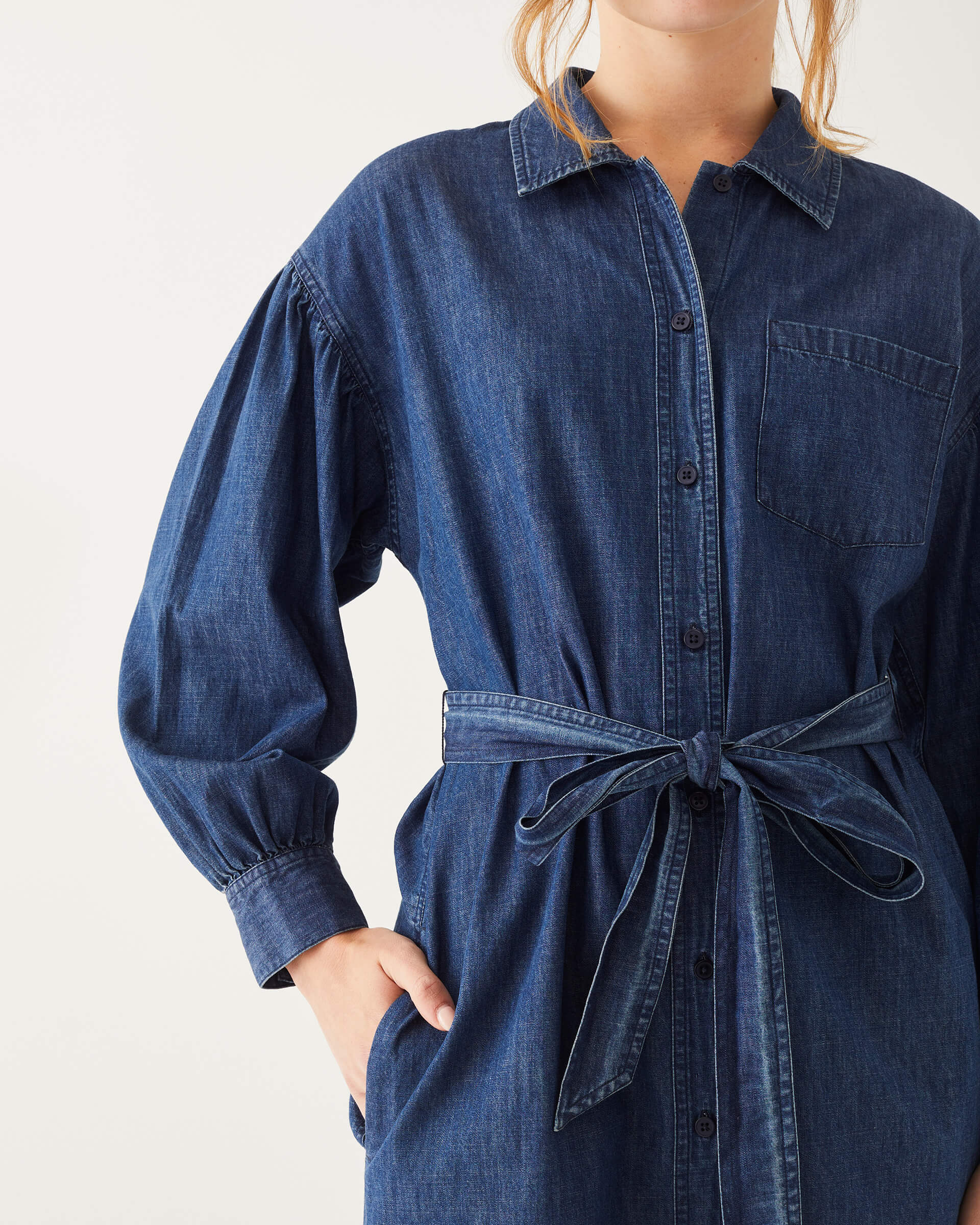 female wearing chambray shirt dress with collar, button-down and belt on a white background