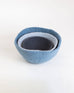 three felt nesting bowls in different sizes and shades of blue stacked together on white background