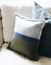 light blue and dark green felt wool pillow sitting on a neutral couch in front of a pillow