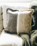 neutral and grey felt wool pillow with a white line across the middle sitting on a couch 