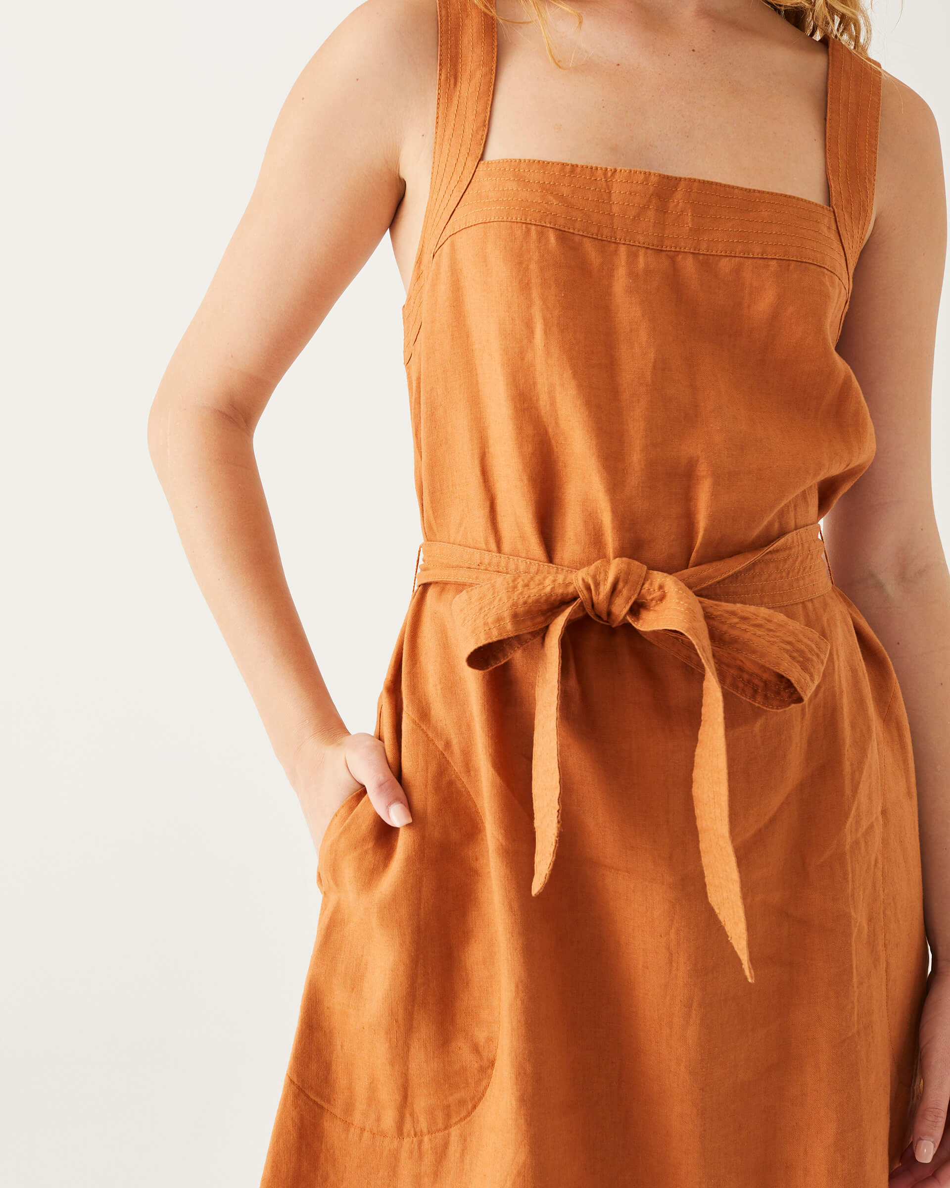 female wearing clay A-line linen sundress with self-belt standing on a white background
