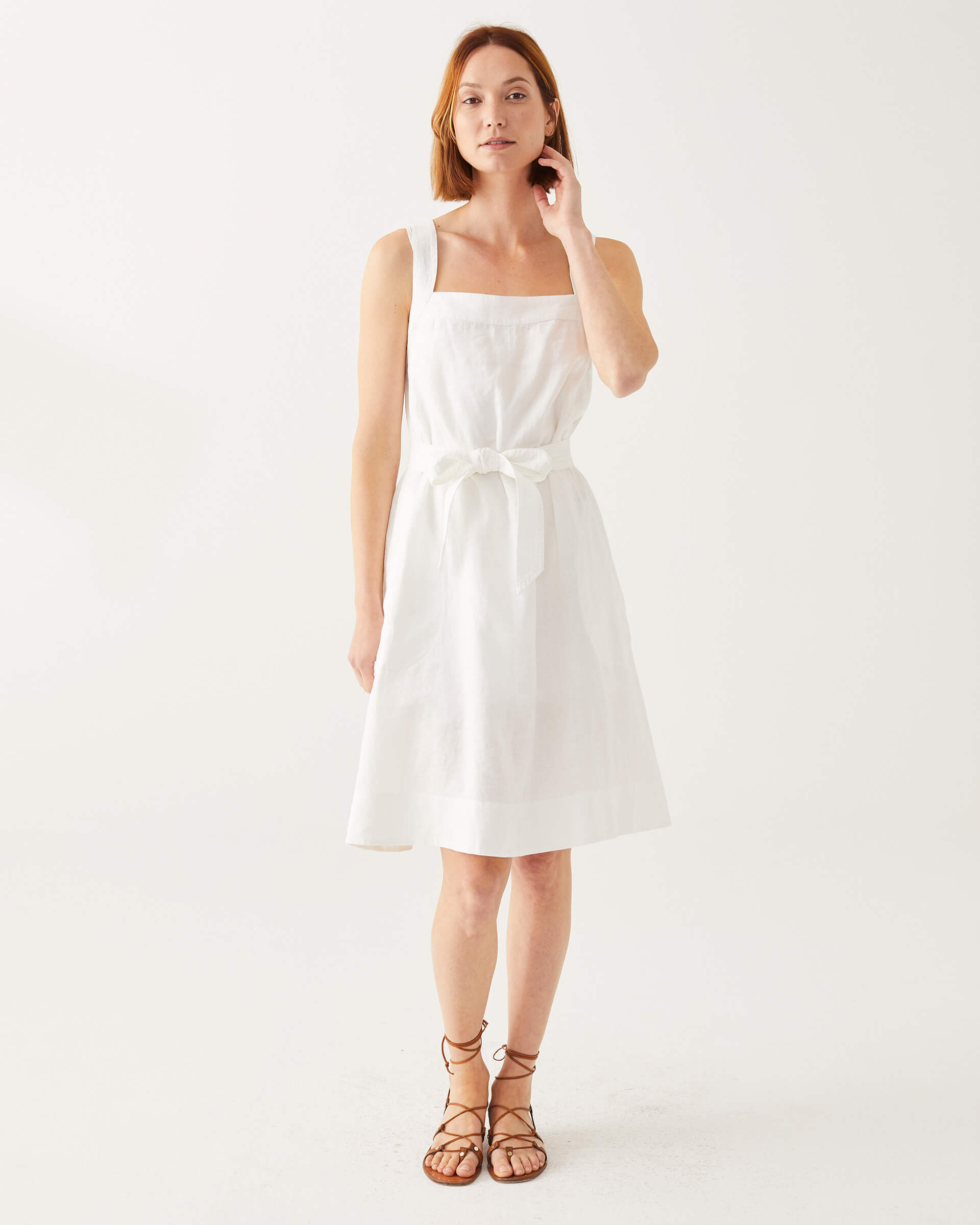 female wearing white A-line linen sundress with self-belt standing on a white background