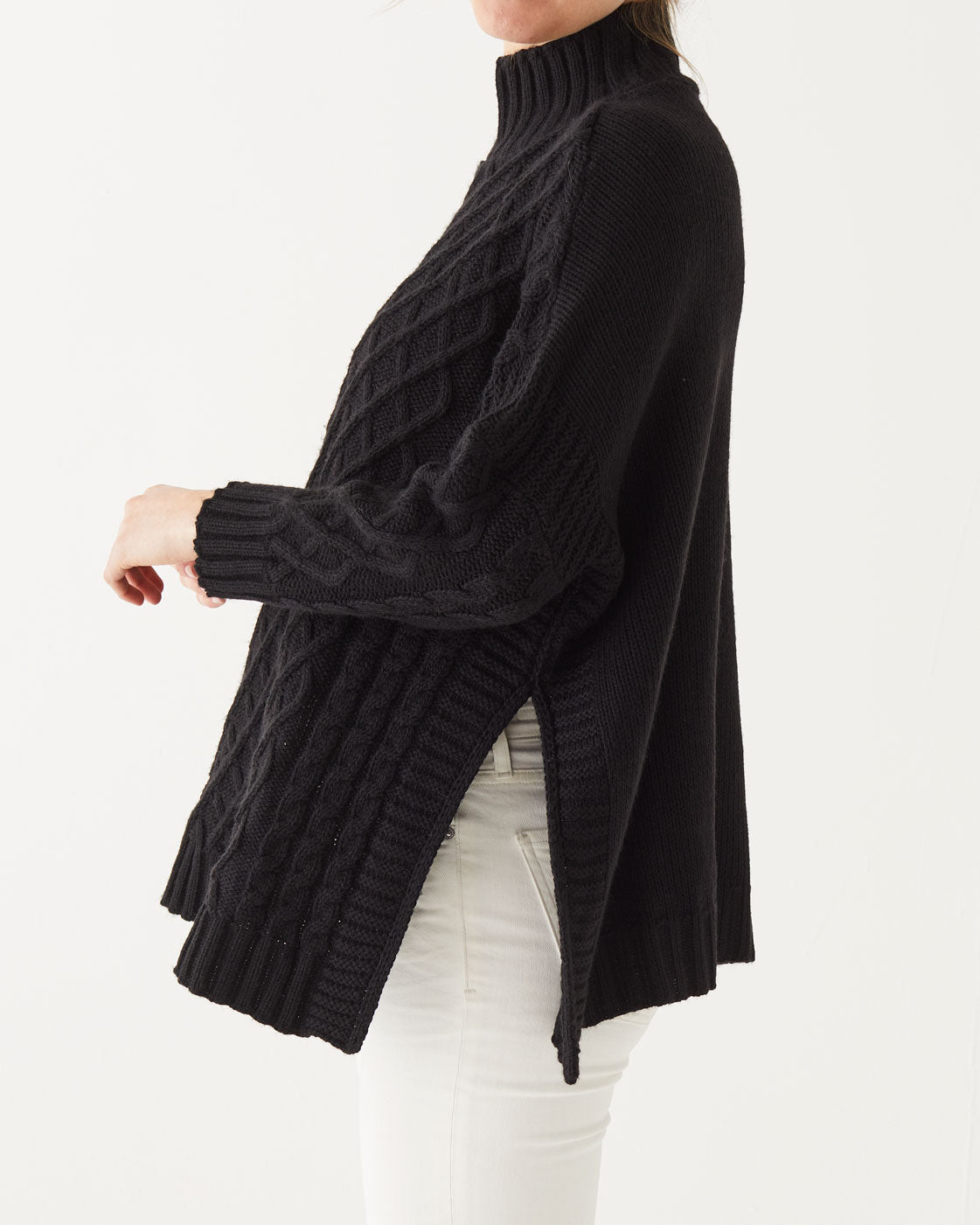 close up of female wearing black sweater standing sideways on a white background 