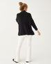 strawberry blonde female wearing black sweater standing backwards on a white background