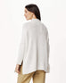 brunette female wearing white sweater standing backwards on a white background
