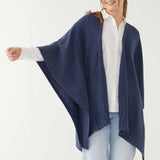 Female wearing a blue wrap over a white button shirt in front of white background