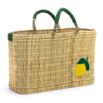 medium sized straw basket with handwoven lemon and green leather handles on a white background