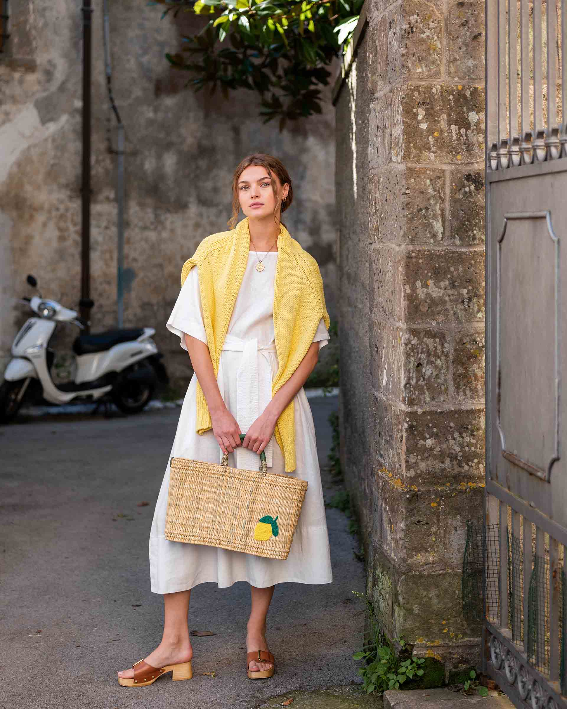 female holding medium sized straw basket with handwoven lemon standing in the street