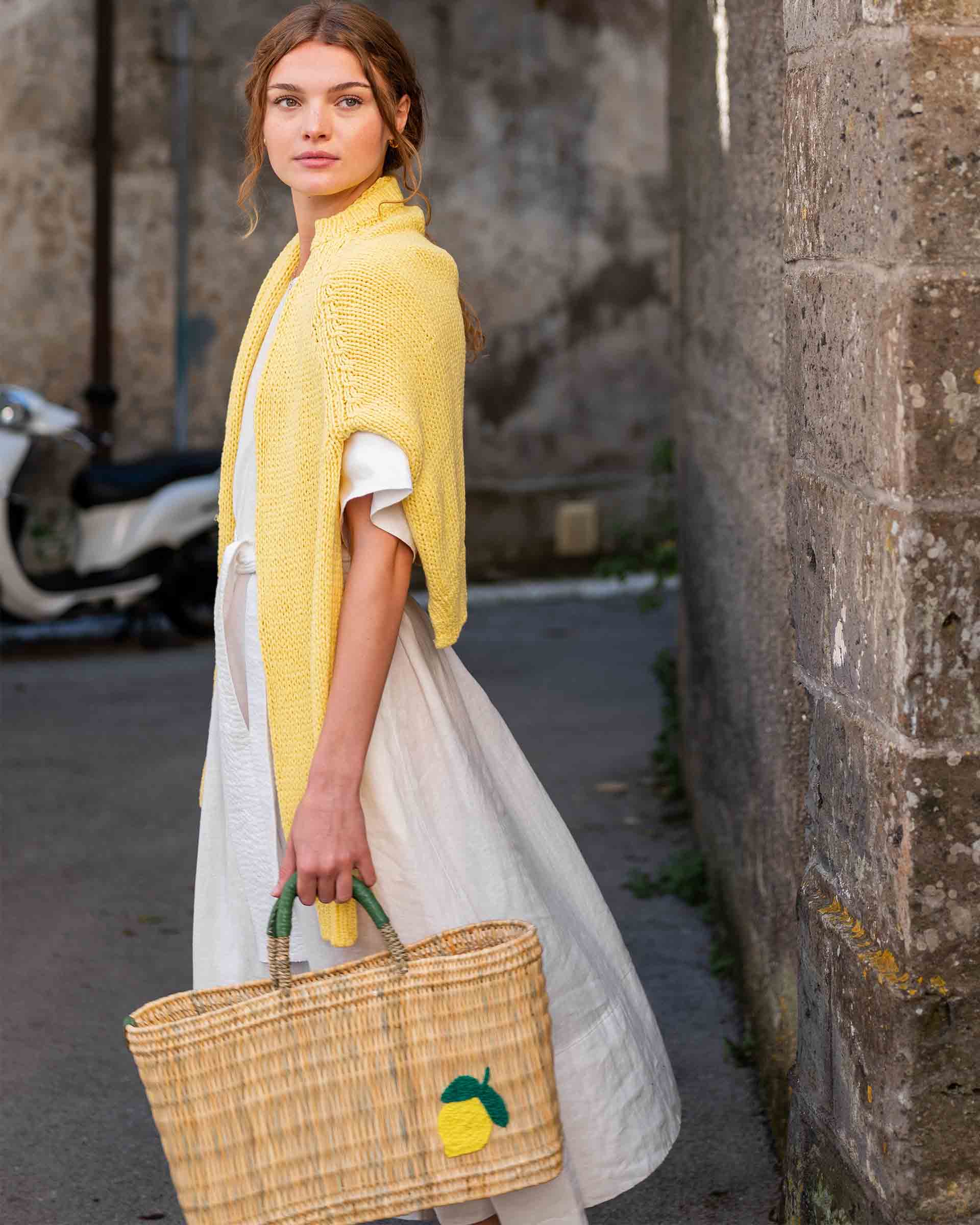 female holding medium sized straw basket with handwoven lemon walking in the street