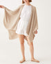 close up of female wearing light brown cable knit wrap swaying on white background
