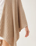 close up of female wearing light brown wrap with cable knit details on a white background
