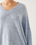 close up of female wearing light blue speckled ribbed v-neck line sweater on a white background