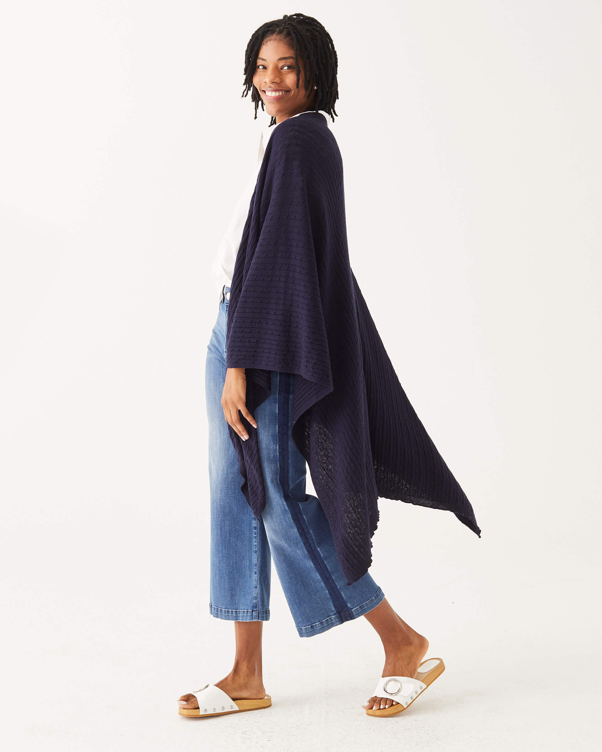 female wearing navy cable knit wrap over her shoulders turned to the side on a white background