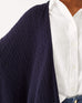 close up of female wearing navy cable knit wrap with cable knit details on a white background
