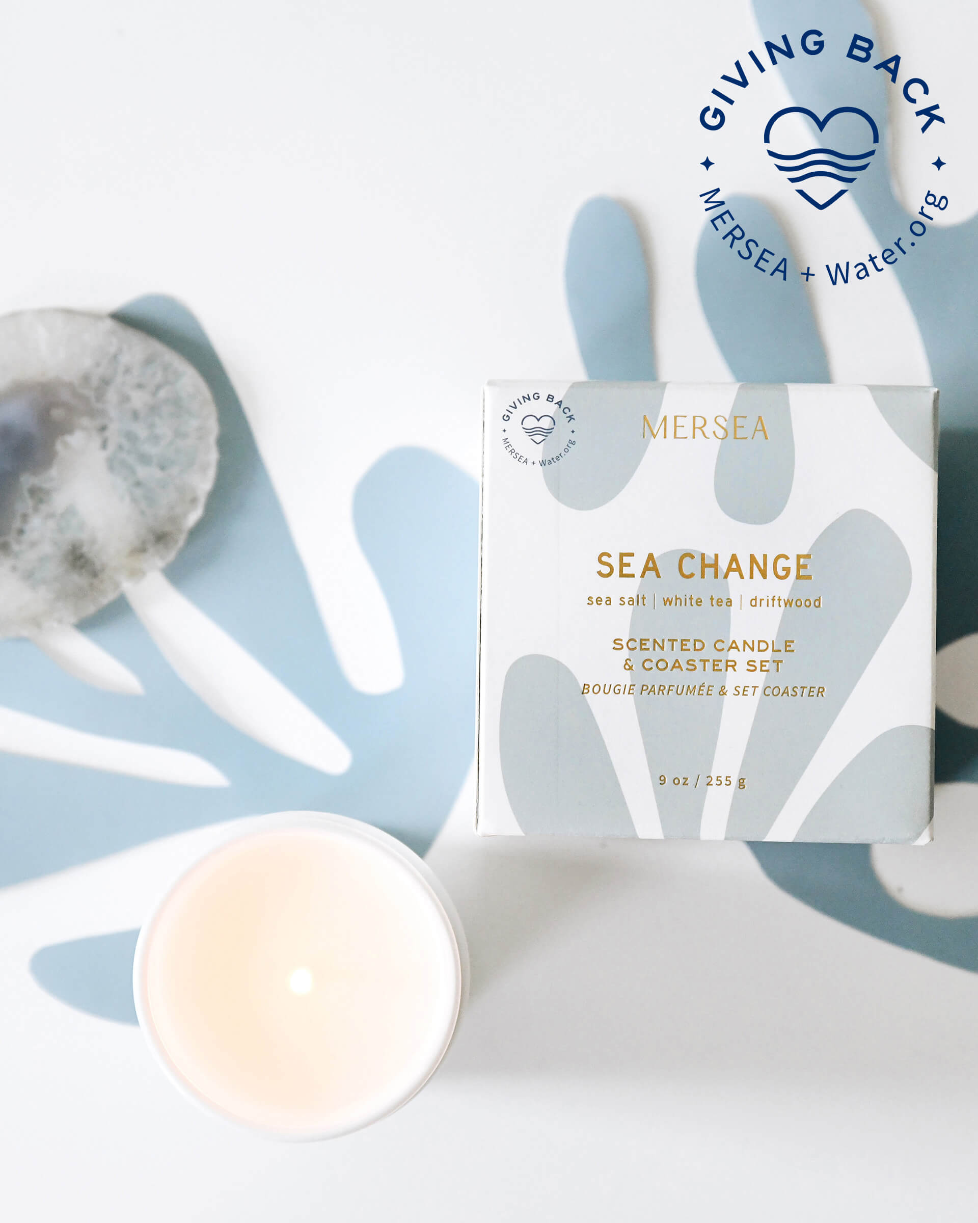 boxed sea change candle with coaster and unboxed white candle on light blue and white background