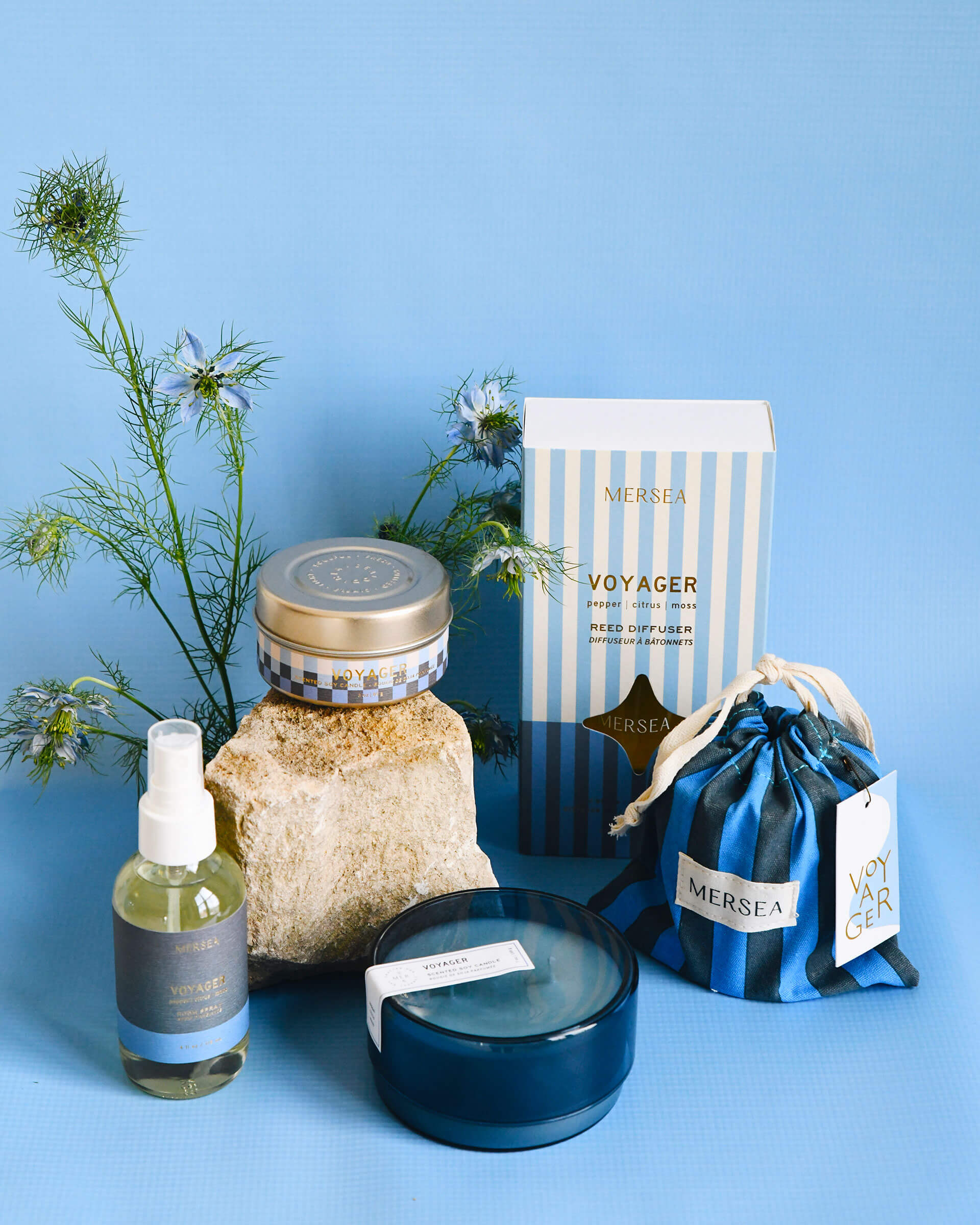 Voyager scented collection of candles, room spray and diffuser in front of blue background