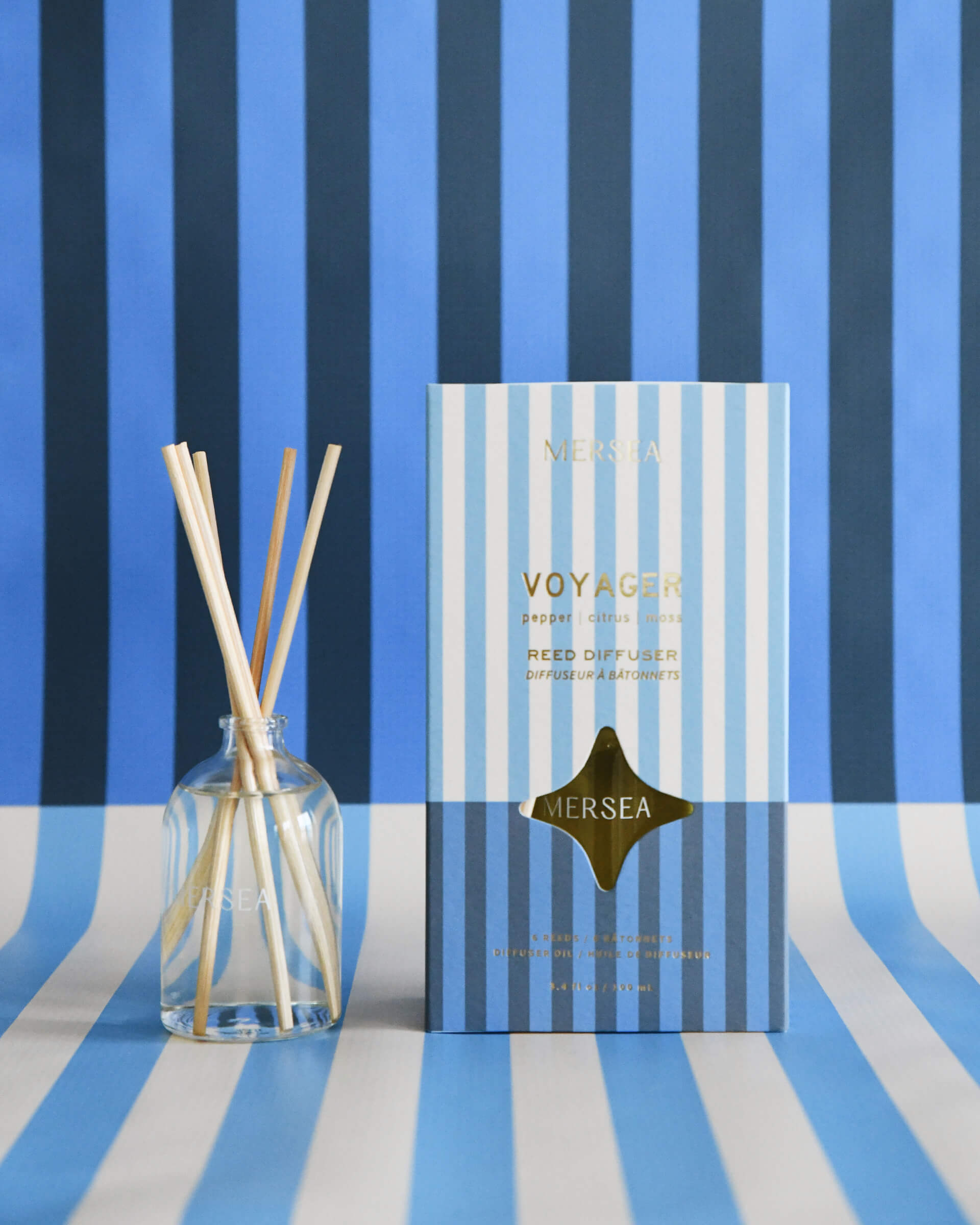 voyager reed diffuser boxed in light and dark blue stripes on light and blue striped background 